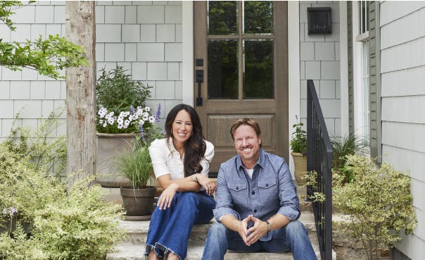 chip and joanna gaines sitting in front of a renovated home featuring hardie siding