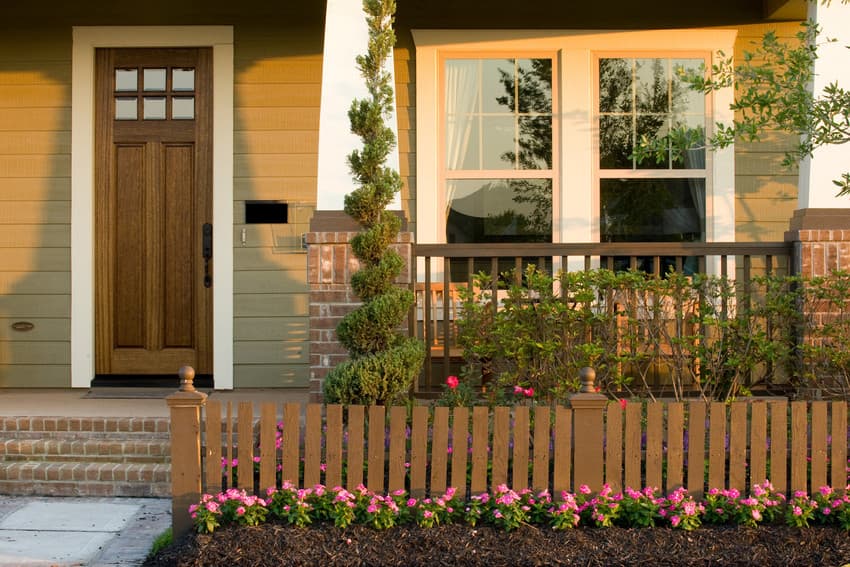 house-landscaping-ideas House with brown lap siding with a garden of pink flowers and shrubbery in front of it.