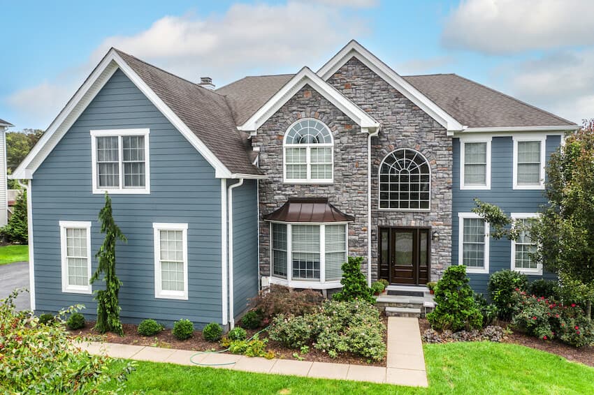 Large suburban home clad with Evening Blue Hardie plank lap siding and Arctic White Hardie trim Large suburban home clad with Evening Blue Hardie plank lap siding and Arctic White Hardie trim