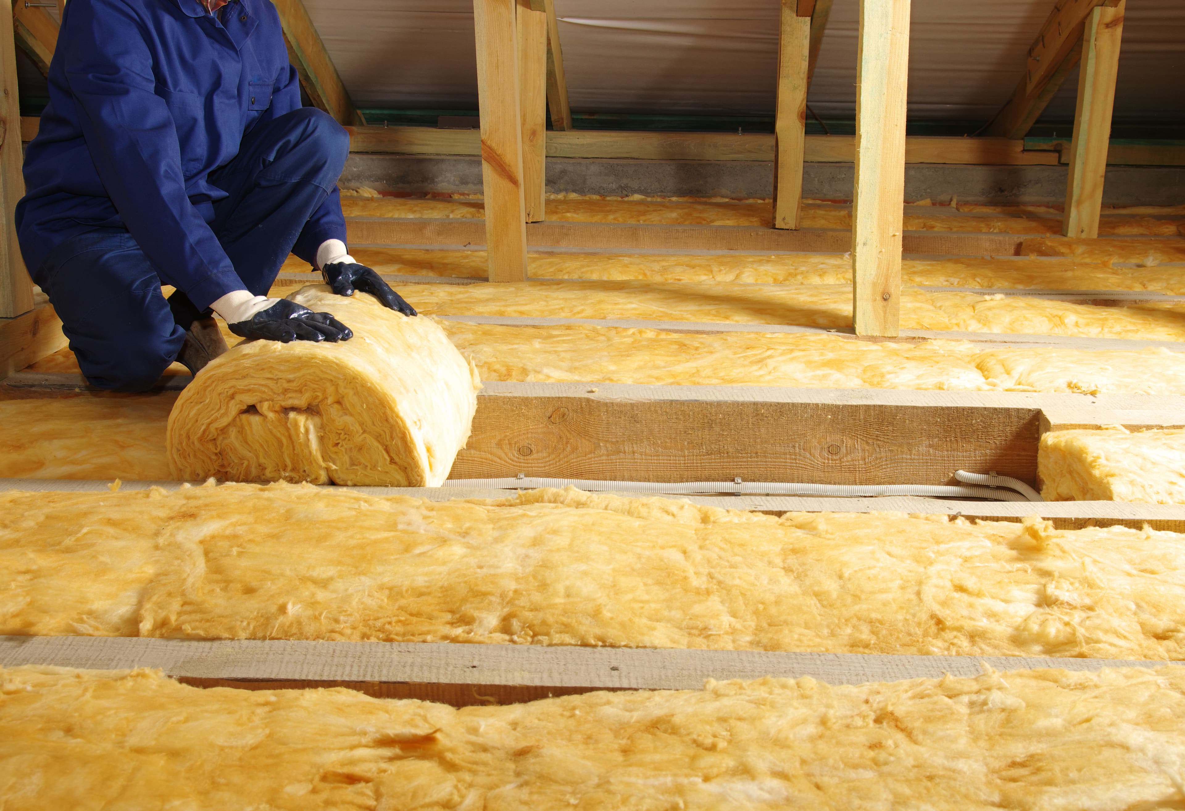 Prepare Your Home for Winter: INSPECT ATTIC INSULATION Worker installing sheets of insulation